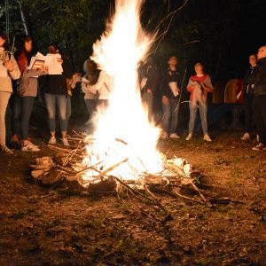 Gruppo di partecipanti attorno a un falò durante un evento interattivo.